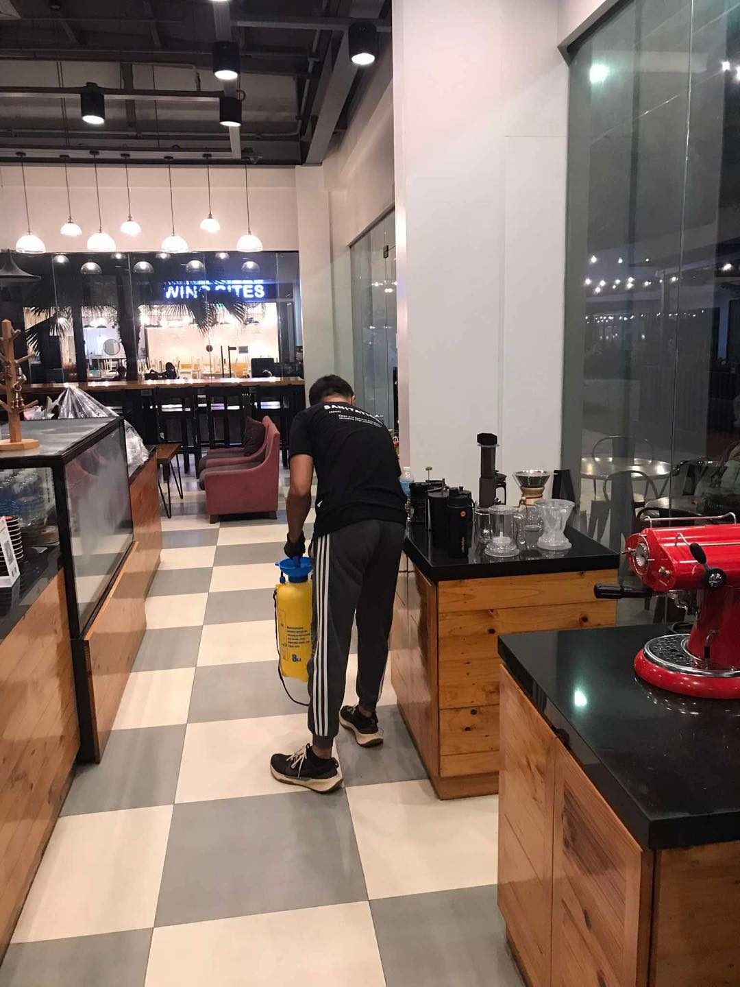 A Molino technician disinfecting a café floor with a pressure sprayer